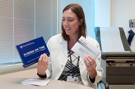 Corinne Rhodes, MD, shows a mailed-home colorectal cancer screening test kit